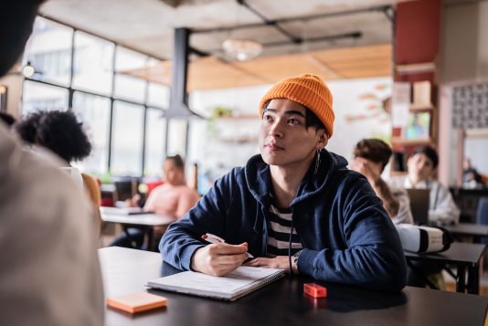 Jeune homme avec un cahier écoute en classe