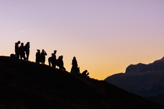 Plusieurs silhouettes sur une colline au coucher de soleil
